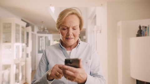 Woman picks up her phone and selects her preferred workout on the bellicon+ platform.