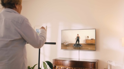 Woman exercises on the bellicon with a video from the bellicon+ training platform.