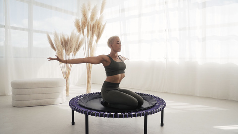 A woman sitting on the bellicon and stretching her upper body.