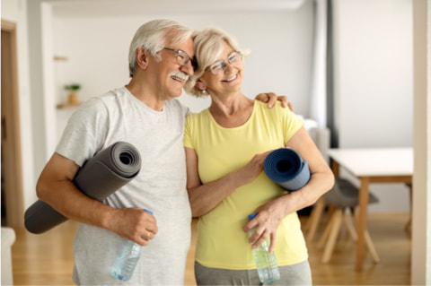 Glückliches älteres Paar mit Trainingsmatte unter dem Arm nach Home Workout.