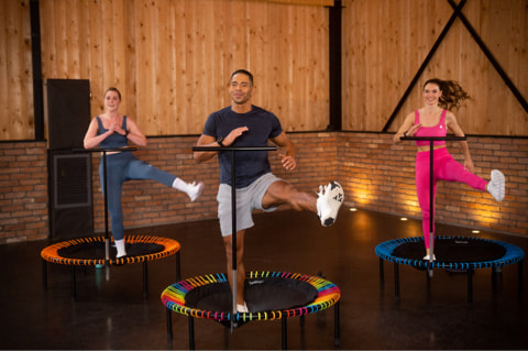 Three people train together on mini trampolines.