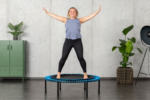 A woman jumps happily on a bellicon mini-trampoline.