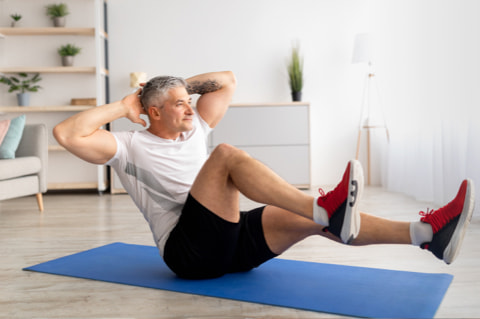 Un homme fait des exercices de musculation sur un tapis de sport dans son salon.